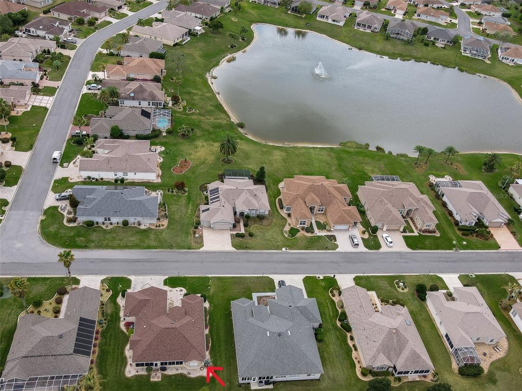 An aerial view shows a suburban neighborhood with single-family homes surrounding a central pond — 9435 SE 124TH PLACE, SUMMERFIELD, FL