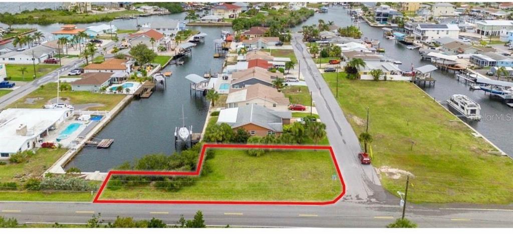 An aerial view shows a vacant, L-shaped waterfront lot outlined in red along a canal — Lot 20 MALCOM AVENUE, HUDSON, FL