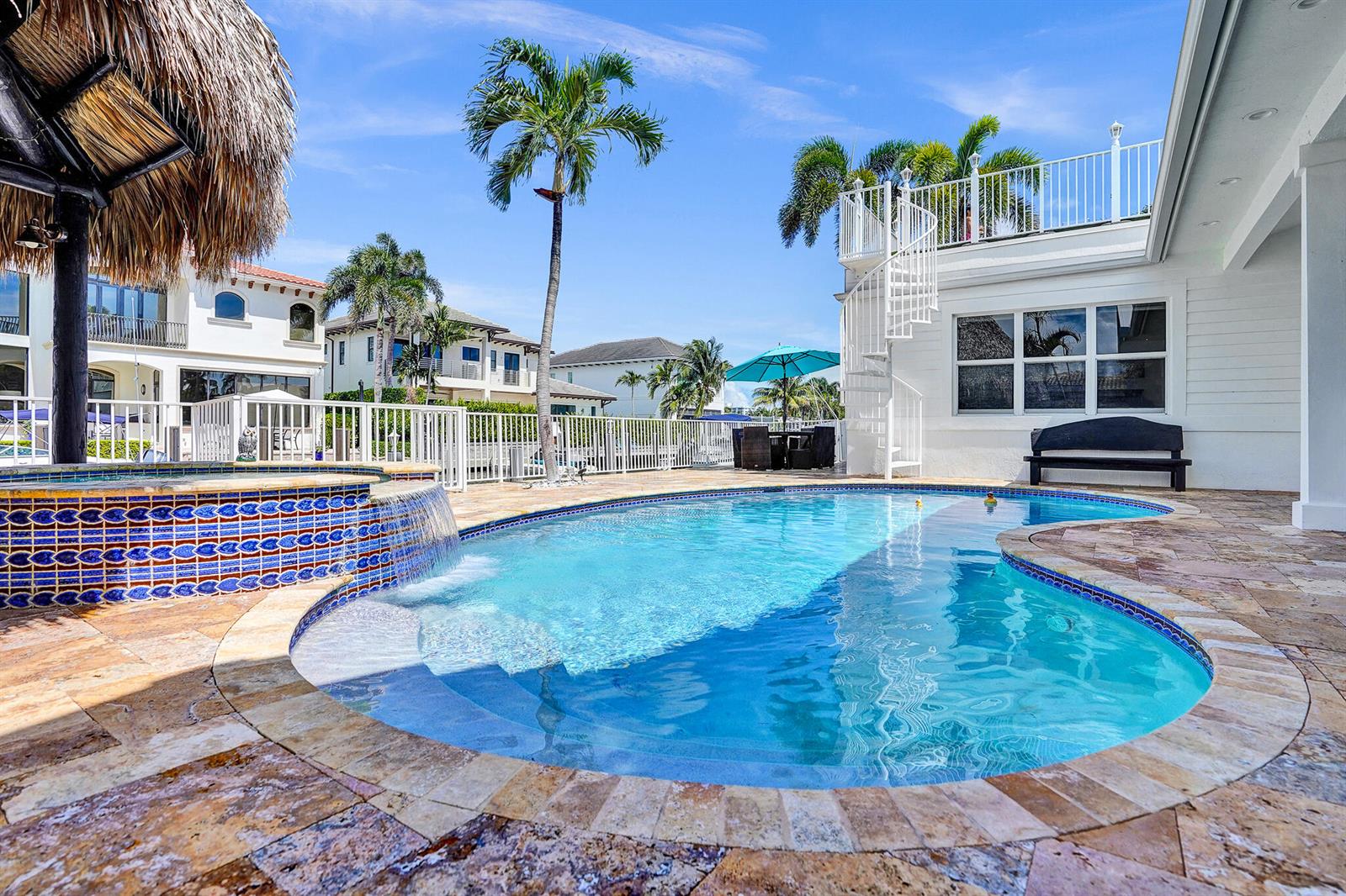 A backyard swimming pool with a spillover spa, stone decking, and a white spiral staircase — 785 NE 71st Street, Boca Raton FL 33487, BOCA RATON, FL