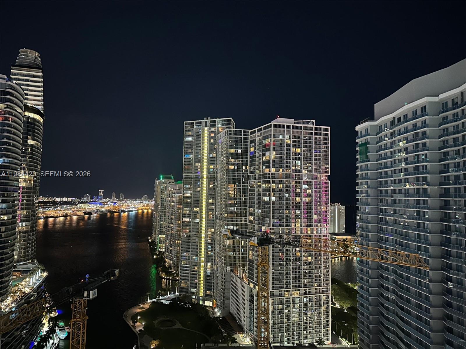An elevated night view of high-rise apartment buildings along a waterfront in a city — 31 SE 5th St # 3916, Miami FL 33131, MIAMI, FL