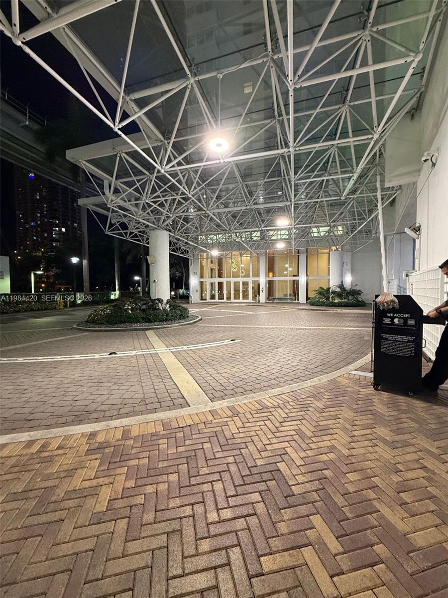 A paved circular driveway leads to the glass-covered entrance of a modern building at night — 31 SE 5th St # 3916, Miami FL 33131, MIAMI, FL