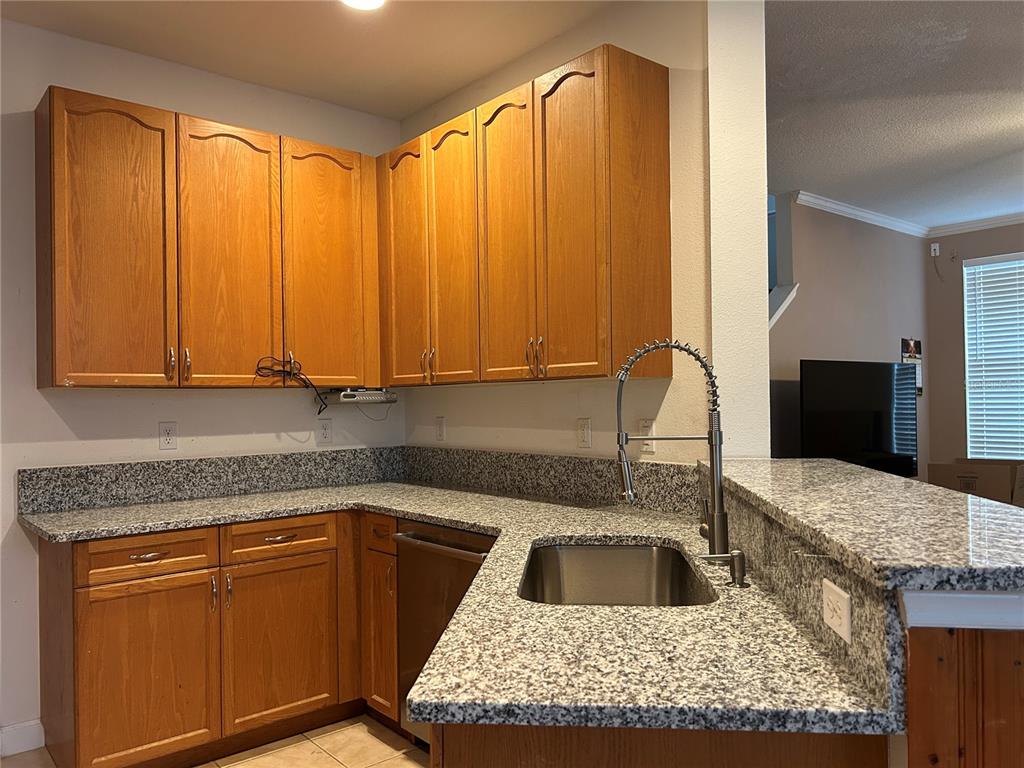 A kitchen features oak cabinets, granite countertops, and a stainless steel sink with a faucet — 2549 TWAIN DRIVE, TALLAHASSEE, FL