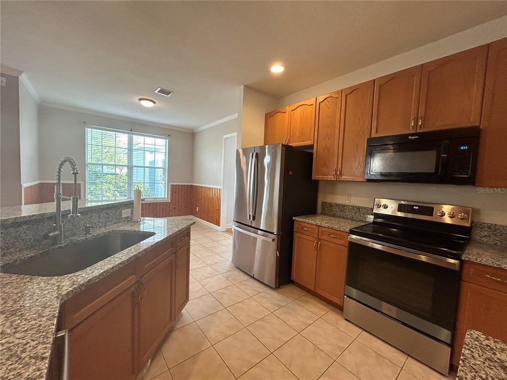 A kitchen with wood cabinets, granite countertops, stainless steel appliances, and tile flooring — 2549 TWAIN DRIVE, TALLAHASSEE, FL