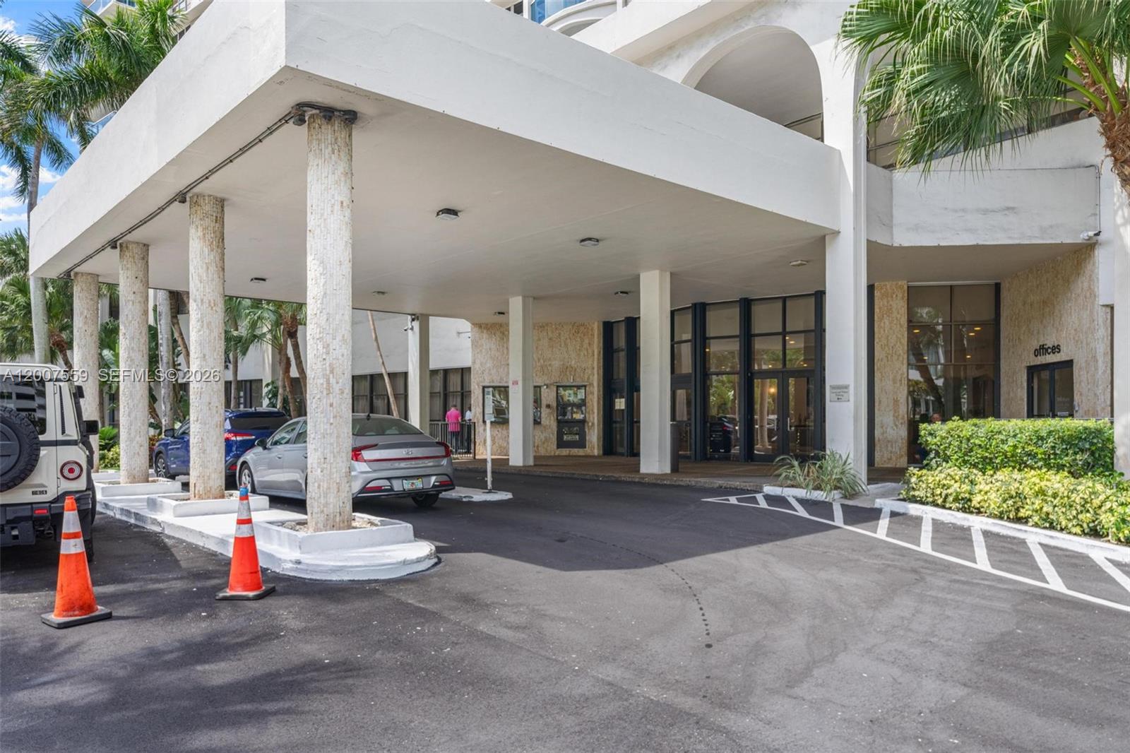 A covered entrance with concrete columns leads to a building with glass doors and offices — 3800 S Ocean Dr # 301, Hollywood FL 33019, HOLLYWOOD, FL