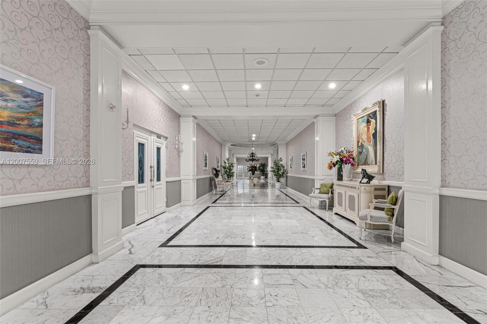 A long, formal hallway features marble flooring, patterned wallpaper, and a drop ceiling — 3800 S Ocean Dr # 301, Hollywood FL 33019, HOLLYWOOD, FL