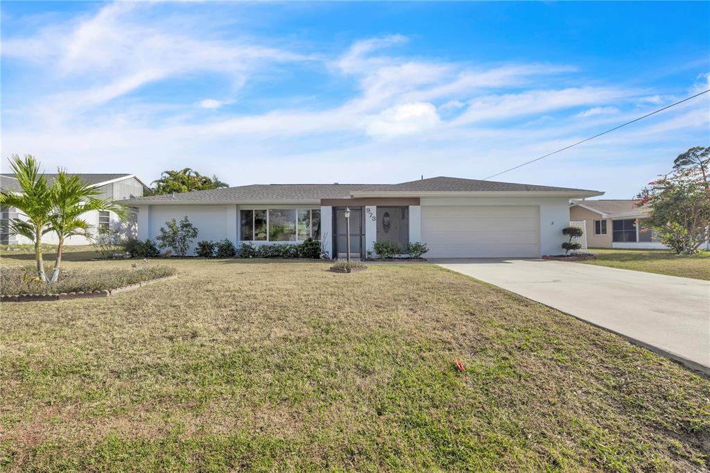 A living room features white leather recliners, a dark wood entertainment center, and large windows — 973 DOBELL TERRACE NW, PORT CHARLOTTE, FL