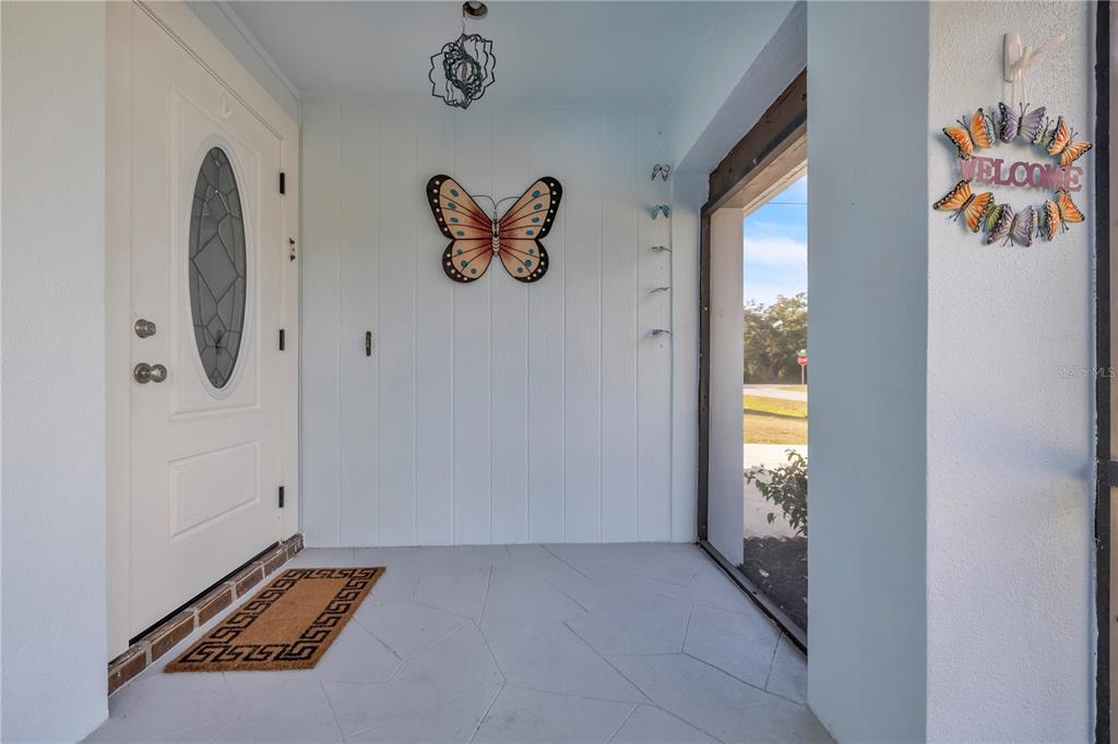 A living room features light wood floors, a white sofa, and large windows with views — 973 DOBELL TERRACE NW, PORT CHARLOTTE, FL