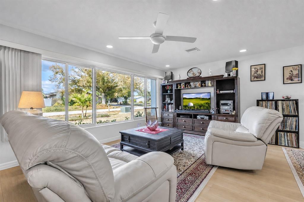 An open-concept living room and kitchen featuring light wood flooring and a large sectional sofa — 973 DOBELL TERRACE NW, PORT CHARLOTTE, FL
