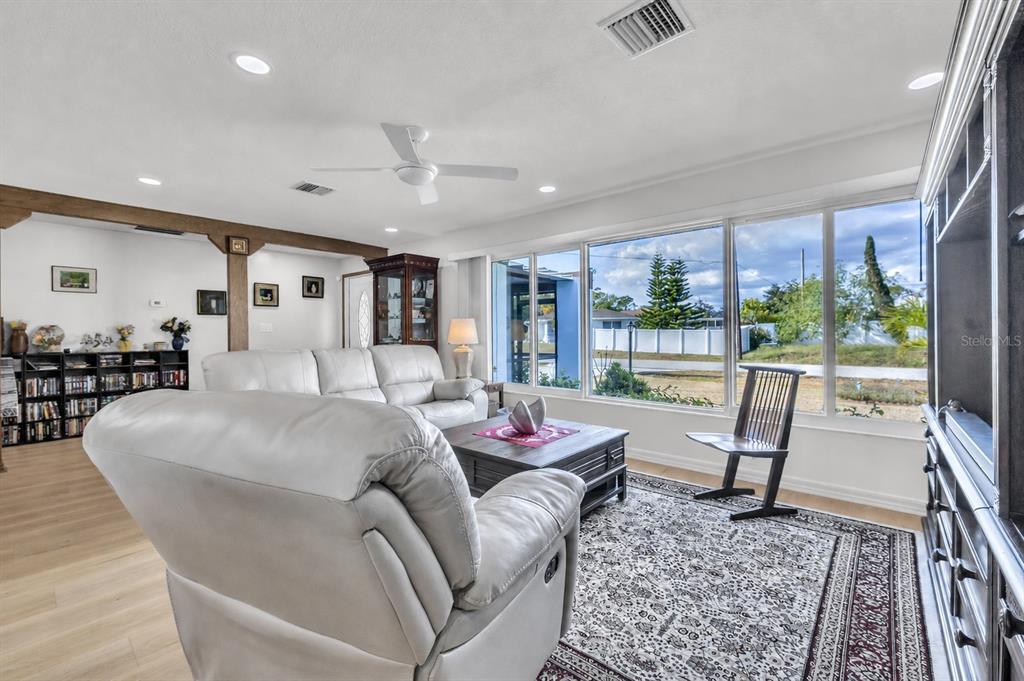 A living room with light-colored leather furniture, a wooden coffee table, and an open kitchen — 973 DOBELL TERRACE NW, PORT CHARLOTTE, FL