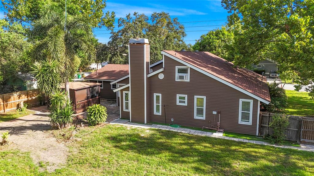 An exterior view of a brown, single-story house with a prominent chimney and a backyard — 1127 WYATT STREET N, CLEARWATER, FL
