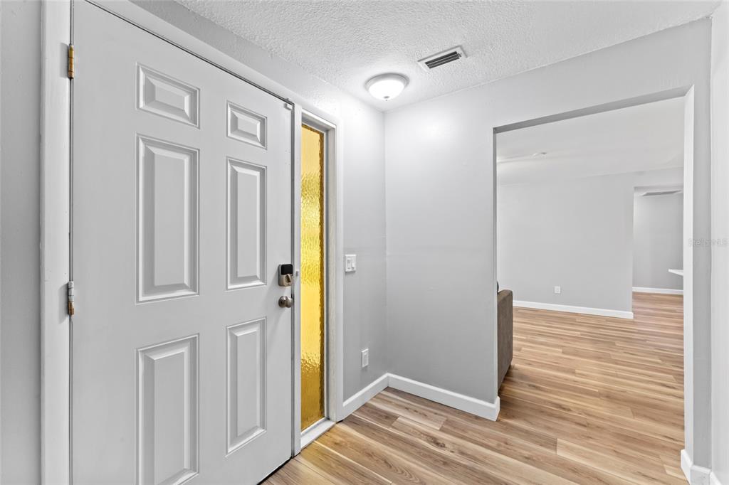 An entryway with a white front door, a sidelight, and light wood-look flooring — 1127 WYATT STREET N, CLEARWATER, FL