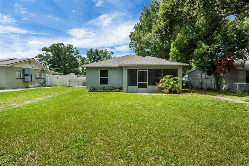 A single-story house with a screened-in porch sits on a grassy lot with trees — 212 PIKE STREET, AUBURNDALE, FL