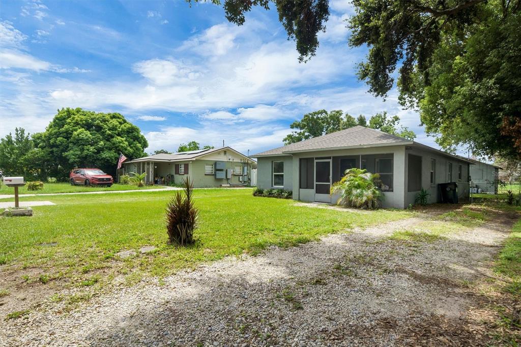 A gravel driveway leads to a single-story house with a screened-in front porch — 212 PIKE STREET, AUBURNDALE, FL
