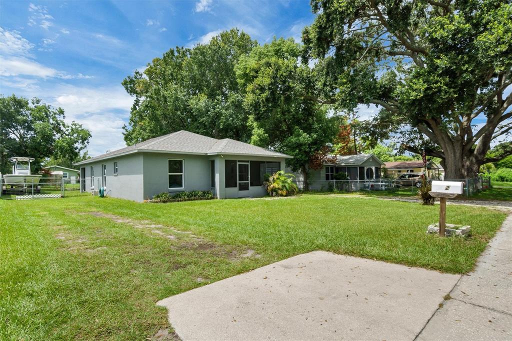 A gray single-story house with a screened porch sits on a grassy lot with trees — 212 PIKE STREET, AUBURNDALE, FL