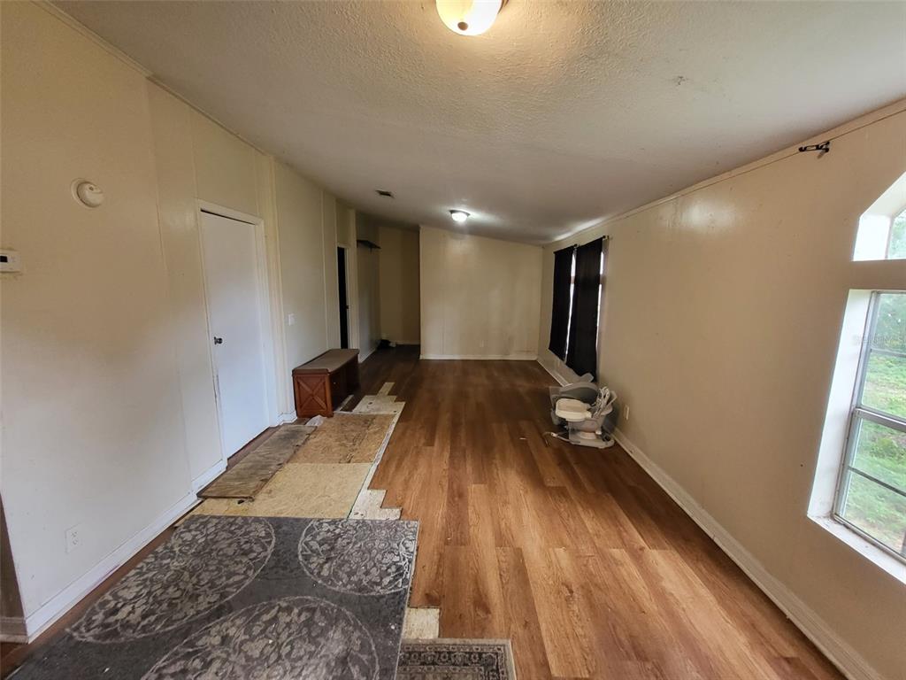 An interior view of a living area with wood-look flooring and unfinished floor sections — 36639 KEEUKA ROAD, ZEPHYRHILLS, FL