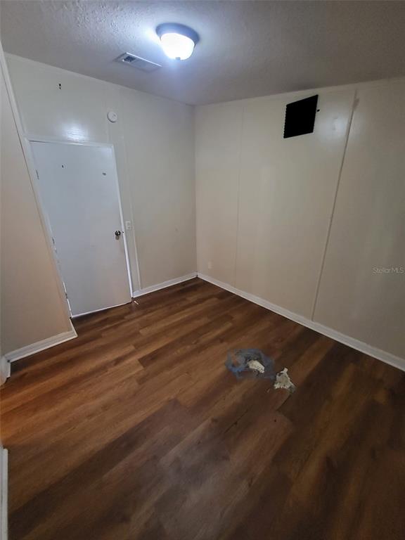 An empty room with light-colored walls, a white door, and dark wood-look flooring — 36639 KEEUKA ROAD, ZEPHYRHILLS, FL