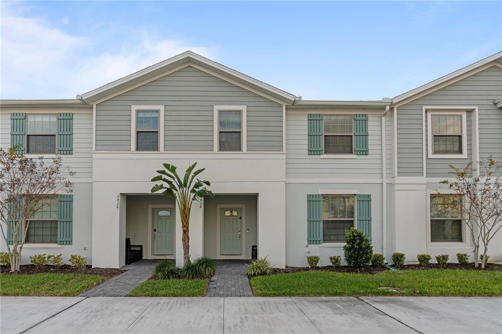 A two-story townhouse exterior features light gray siding, stucco accents, and two front entry doors — 2428 DUBAI STREET, KISSIMMEE, FL