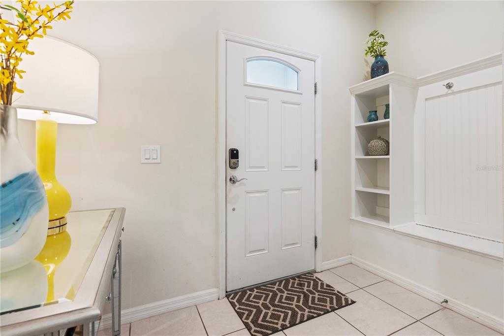 An entryway features a white front door, a built-in storage bench, and a console table — 2428 DUBAI STREET, KISSIMMEE, FL