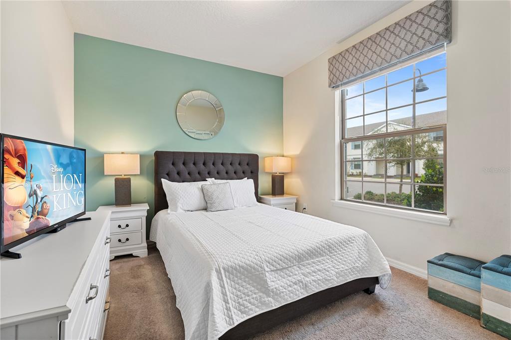 A bedroom features a tufted headboard, a mint green accent wall, and a large window — 2428 DUBAI STREET, KISSIMMEE, FL