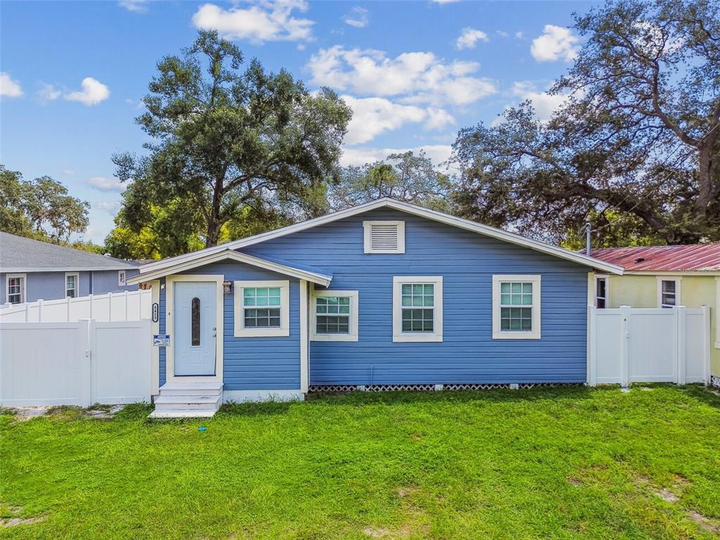 A blue, single-story house with white trim and a white vinyl fence in the yard — 8413 N HAMNER AVENUE, TAMPA, FL