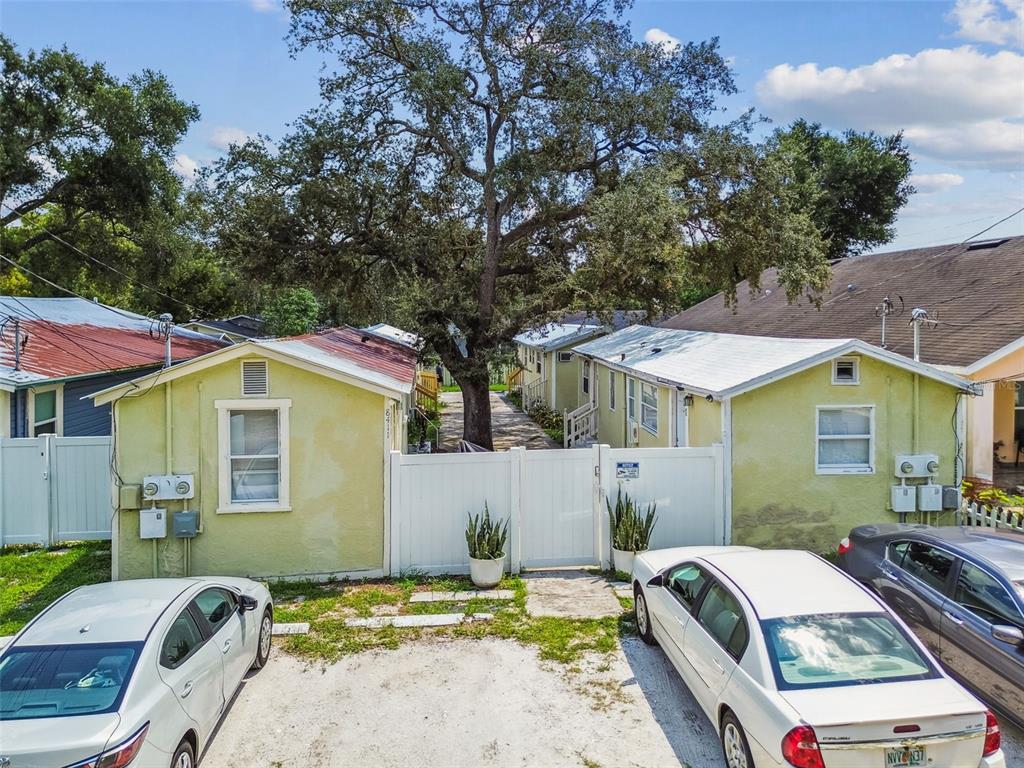 Two light green houses with white roofs are separated by a white gate and tree — 8413 N HAMNER AVENUE, TAMPA, FL