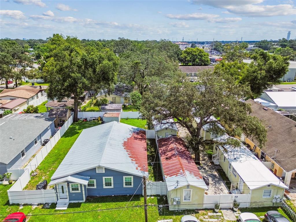 An aerial view shows two adjacent houses with metal roofs and a large shade tree — 8413 N HAMNER AVENUE, TAMPA, FL