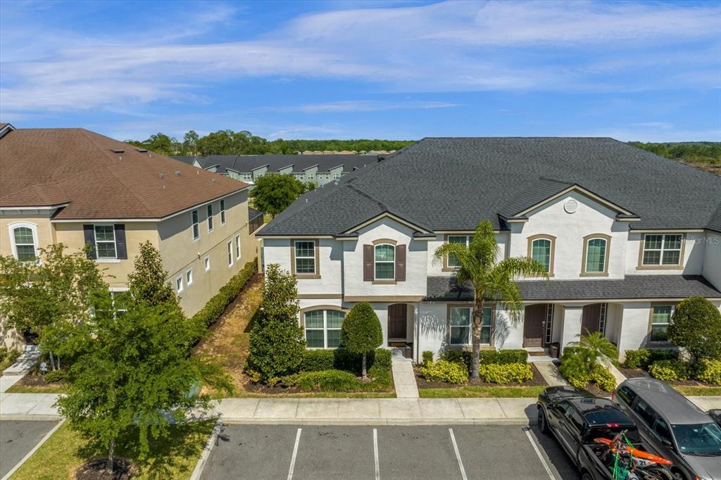 An exterior view of a two-story townhouse with a white facade and dark roof — 1555 CAREY PALM CIRCLE, KISSIMMEE, FL