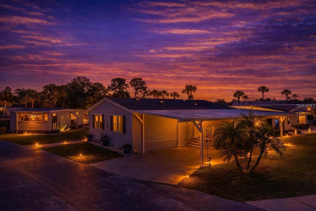 An exterior view of a single-story house with a carport at sunset — 1000 KINGS HIGHWAY UNIT 133, PUNTA GORDA, FL