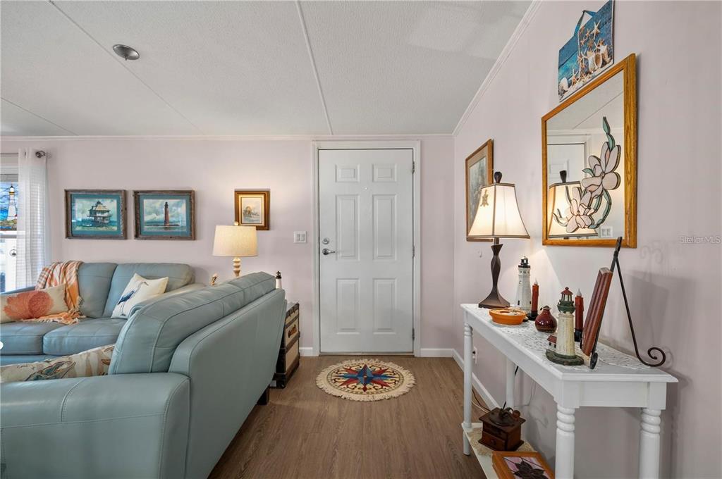 A living room features a light blue sofa, a white entry door, and a console table — 1000 KINGS HIGHWAY UNIT 133, PUNTA GORDA, FL