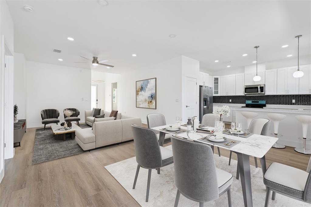 An open-concept living and dining area features white cabinetry, a marble-topped table, and wood flooring — 2713 SAN LUIS ROAD, HOLIDAY, FL