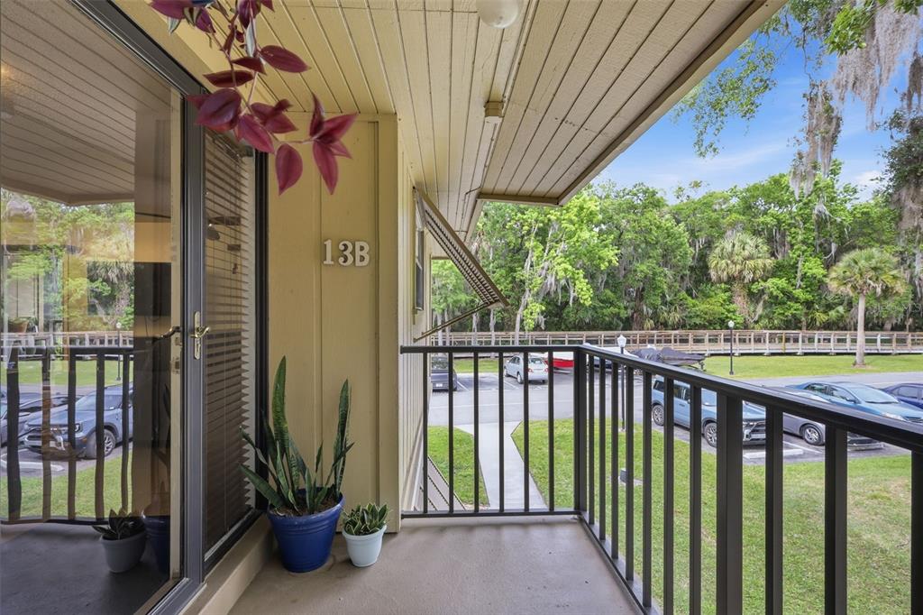 A balcony with a metal railing overlooks a parking lot and trees — 140 ORCHID WOODS COURT UNIT 13B, DELTONA, FL
