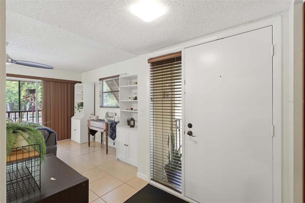 An interior view of an entryway with tile flooring, a white door, and built-in shelving — 140 ORCHID WOODS COURT UNIT 13B, DELTONA, FL