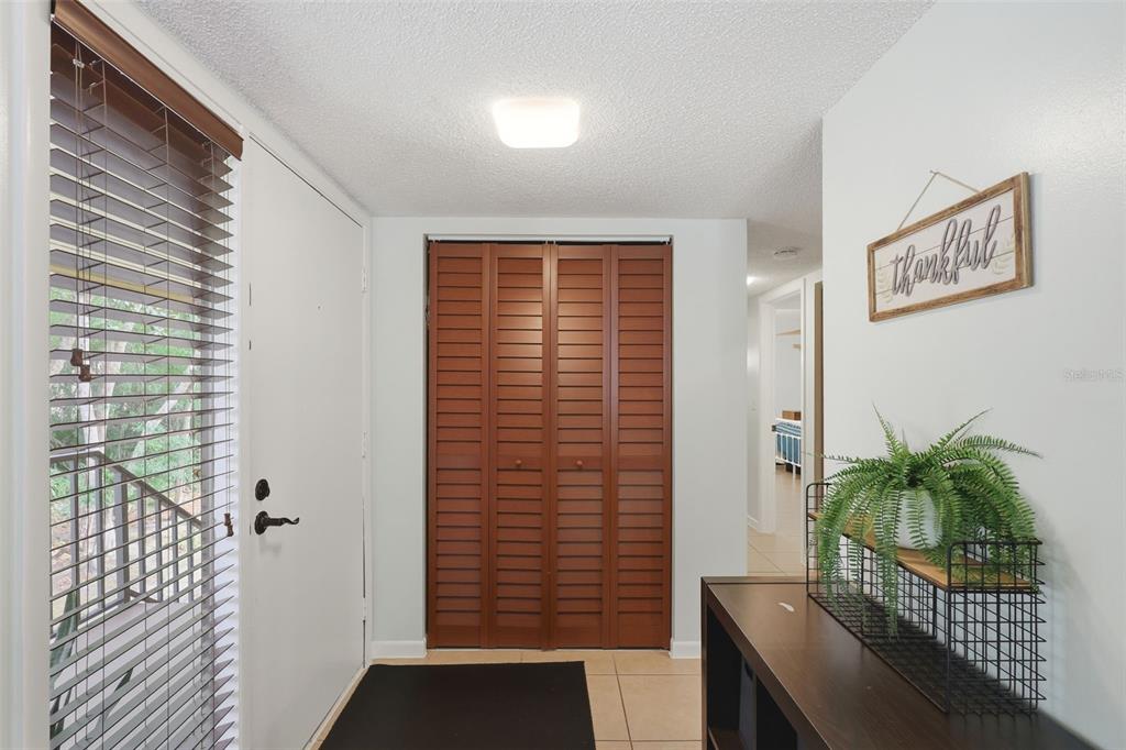 An entryway features a white front door, a louvered wood closet, and a console table — 140 ORCHID WOODS COURT UNIT 13B, DELTONA, FL