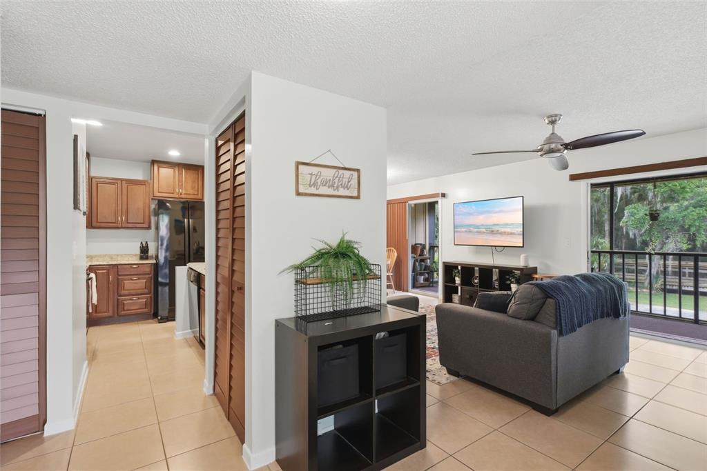 A living room with tile floors and a ceiling fan opens to a kitchen area — 140 ORCHID WOODS COURT UNIT 13B, DELTONA, FL
