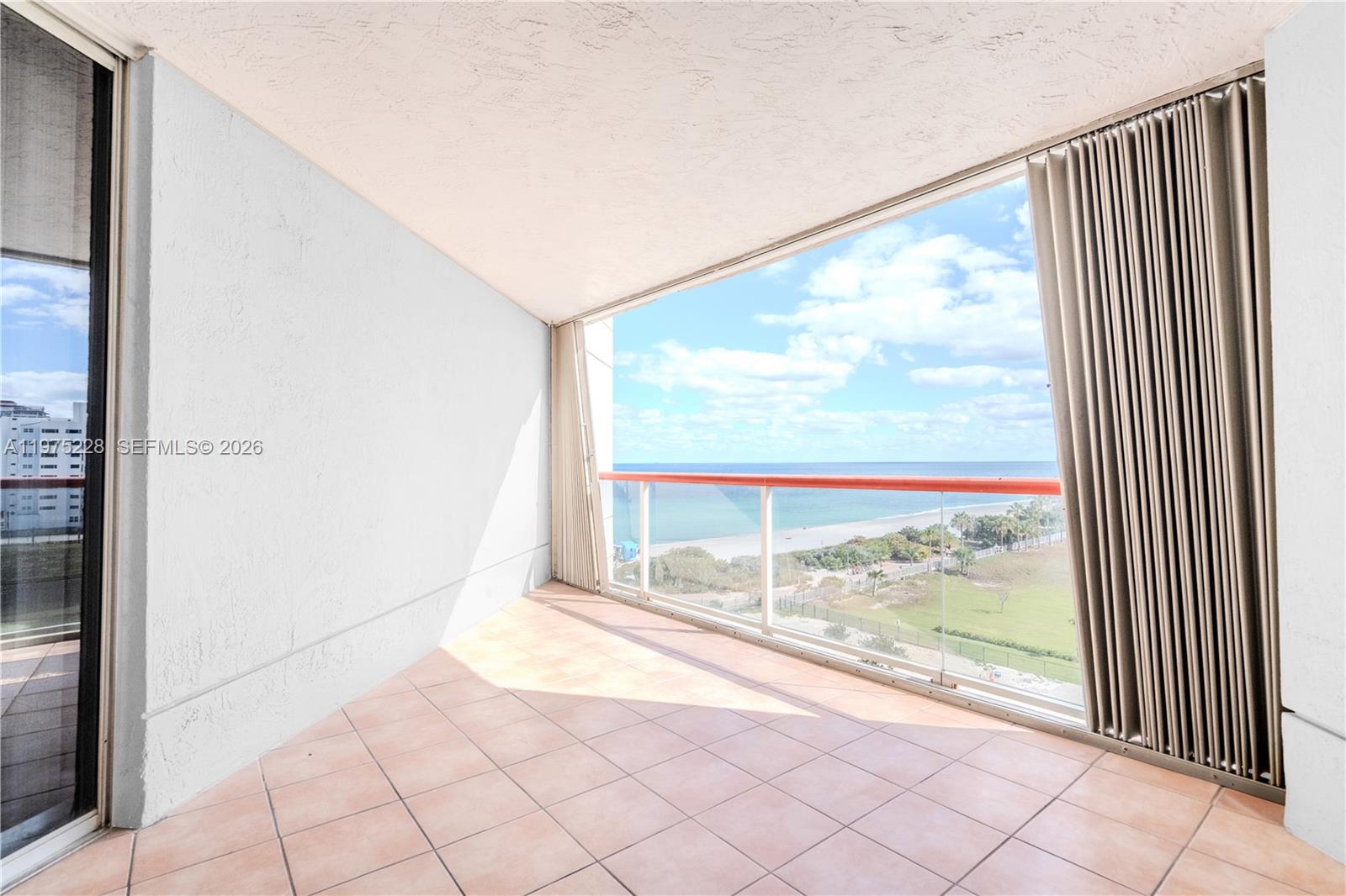 A tiled balcony features a glass railing overlooking the ocean and a sandy beach — 6767 Collins Ave # 706, Miami Beach FL 33141, MIAMI BEACH, FL