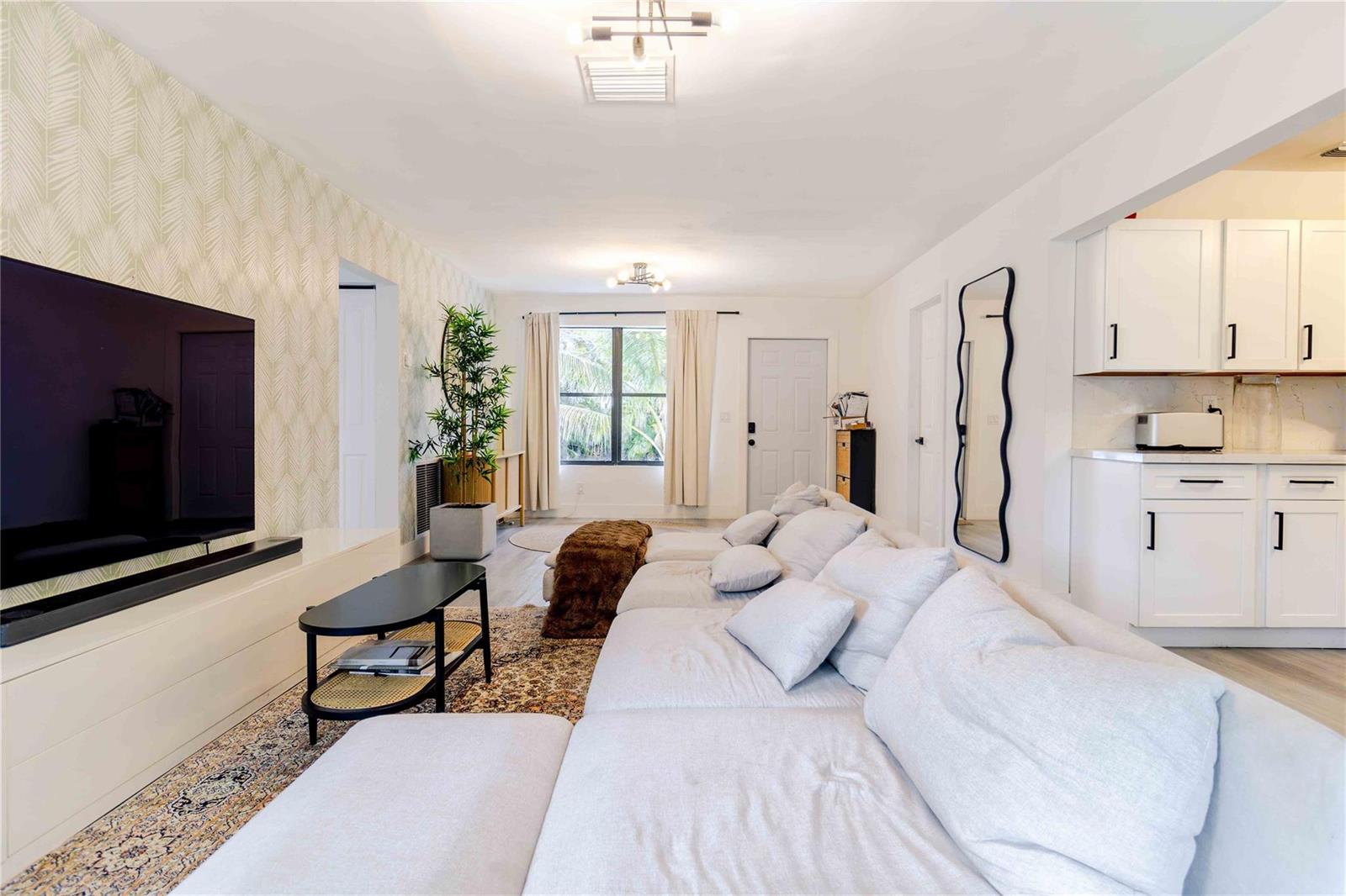 A living room features a large sectional sofa, a television, and an adjacent white kitchen — 2515 NE 207th Street, Miami FL 33180, MIAMI, FL