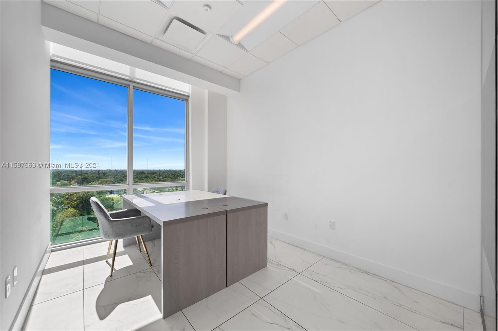 A modern office features a gray desk, a chair, white tile floors, and large windows — 800 SE 4th Ave # 817, Hallandale Beach FL 33009, HALLANDALE BEACH, FL