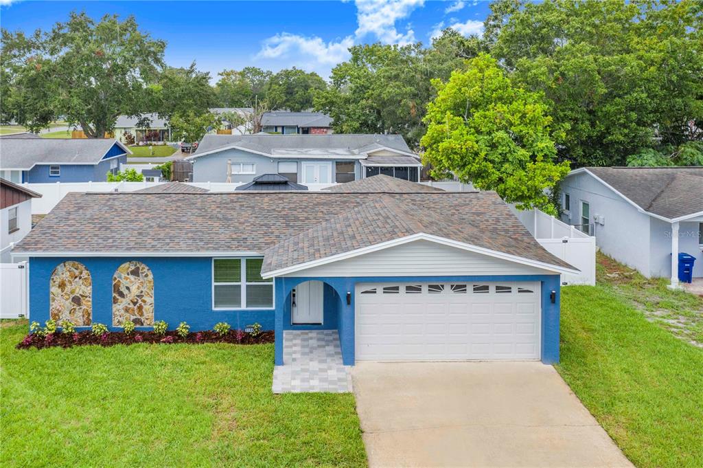 A blue single-story house with a two-car garage and stone accents on the front facade — 3104 ASH COURT, DUNEDIN, FL