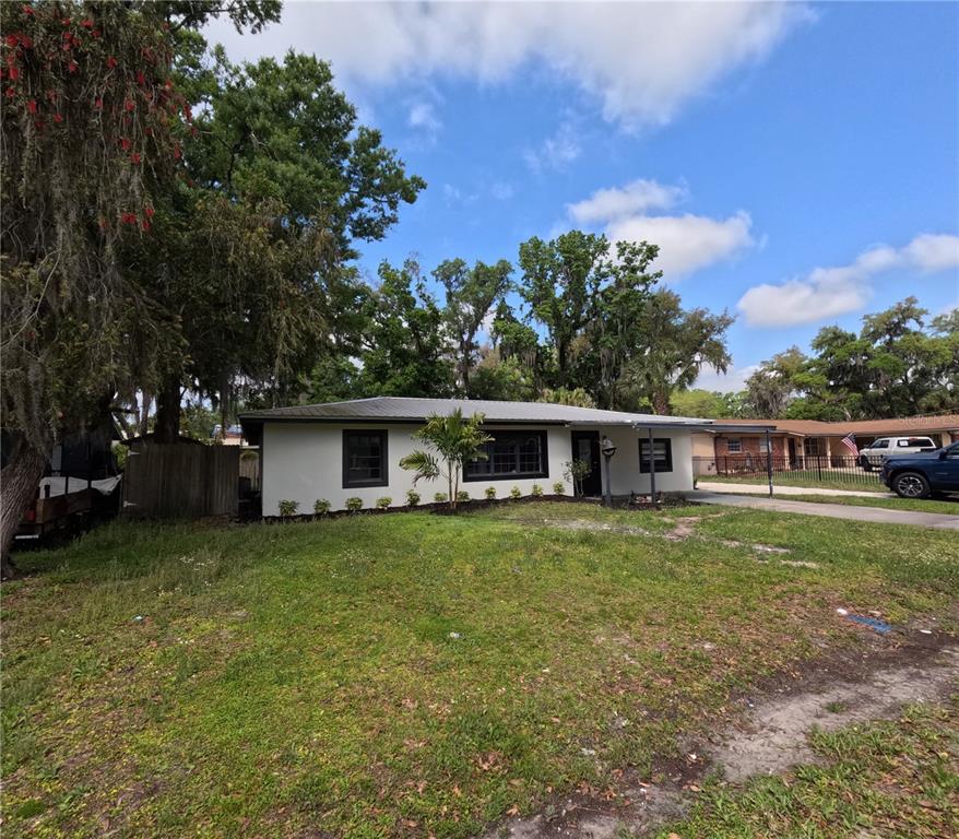 A single-story white house with a dark roof and black window frames sits on grass — 1103 N PENNSYLVANIA AVENUE, PLANT CITY, FL