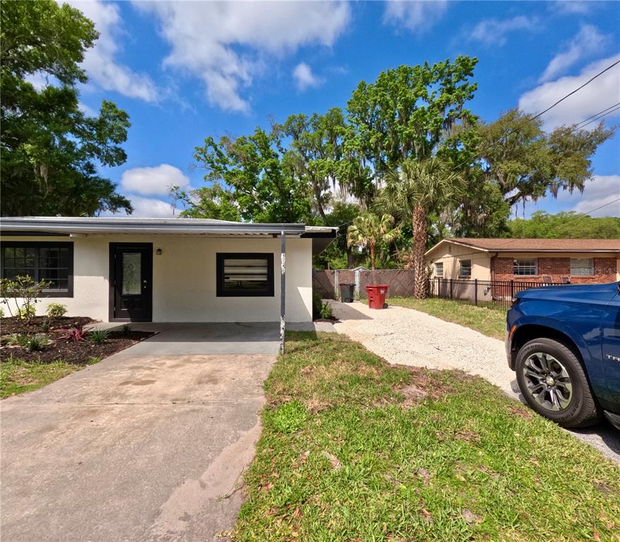 A white house with a covered entryway, concrete driveway, and gravel side path — 1103 N PENNSYLVANIA AVENUE, PLANT CITY, FL