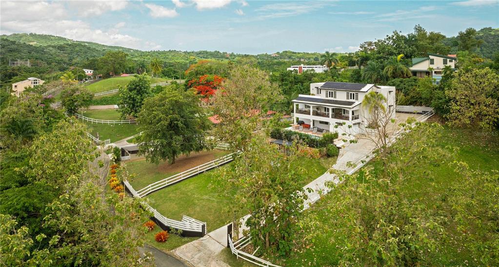 An aerial view of a multi-story white house with a pool and fenced yard — Lot-7 MAMEYES I, HACIENDA PANORAMA, LUQUILLO, PR