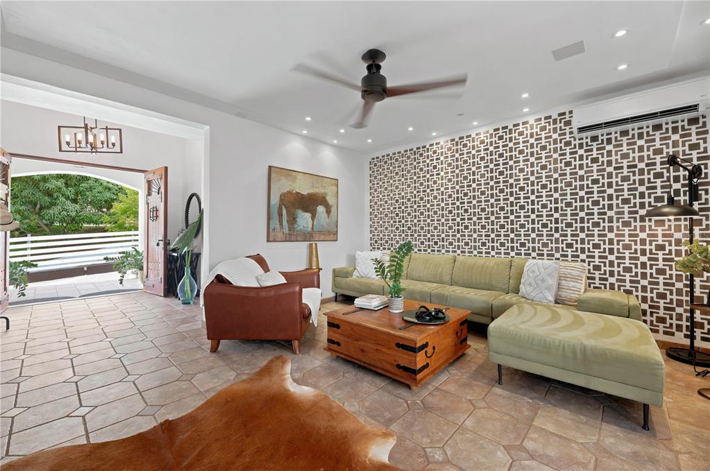 A living room features a patterned accent wall, a green sectional, and tile flooring — Lot-7 MAMEYES I, HACIENDA PANORAMA, LUQUILLO, PR