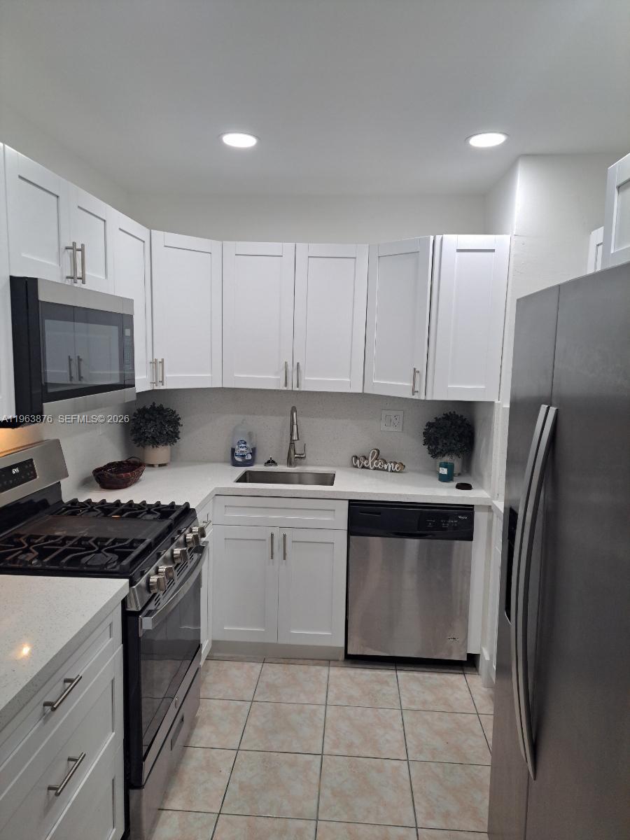 A kitchen features white cabinets, stainless steel appliances, and light-colored countertops — 3020 E Missionwood Ln # 56, Miramar FL 33025, MIRAMAR, FL