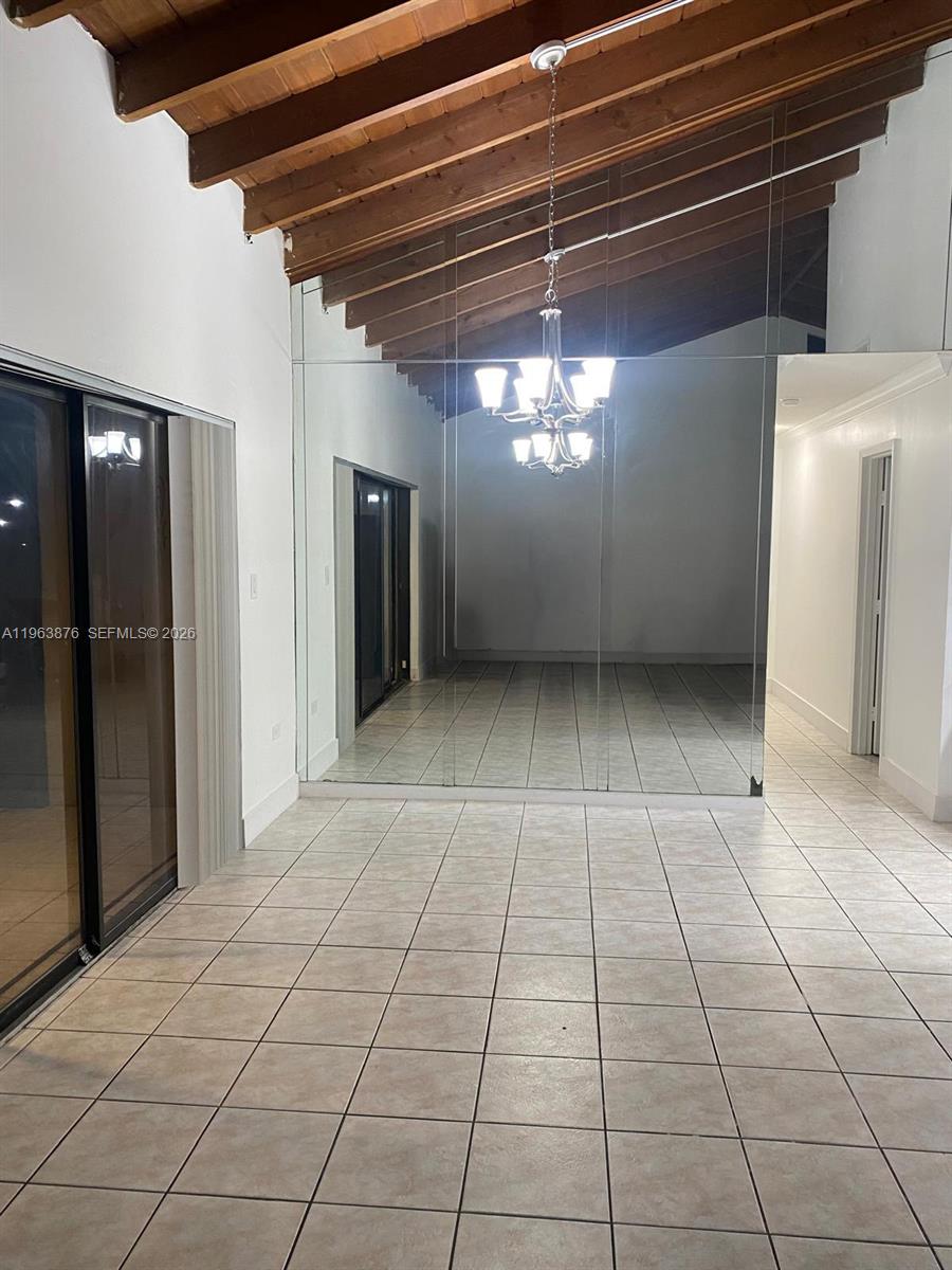 A room with tiled floors, a vaulted wood-beam ceiling, and a large mirrored wall — 3020 E Missionwood Ln # 56, Miramar FL 33025, MIRAMAR, FL
