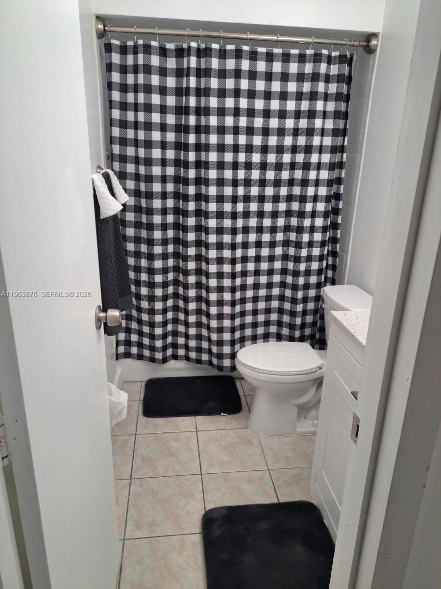 A small bathroom features a white toilet, a vanity, and a black-and-white buffalo check curtain — 3020 E Missionwood Ln # 56, Miramar FL 33025, MIRAMAR, FL