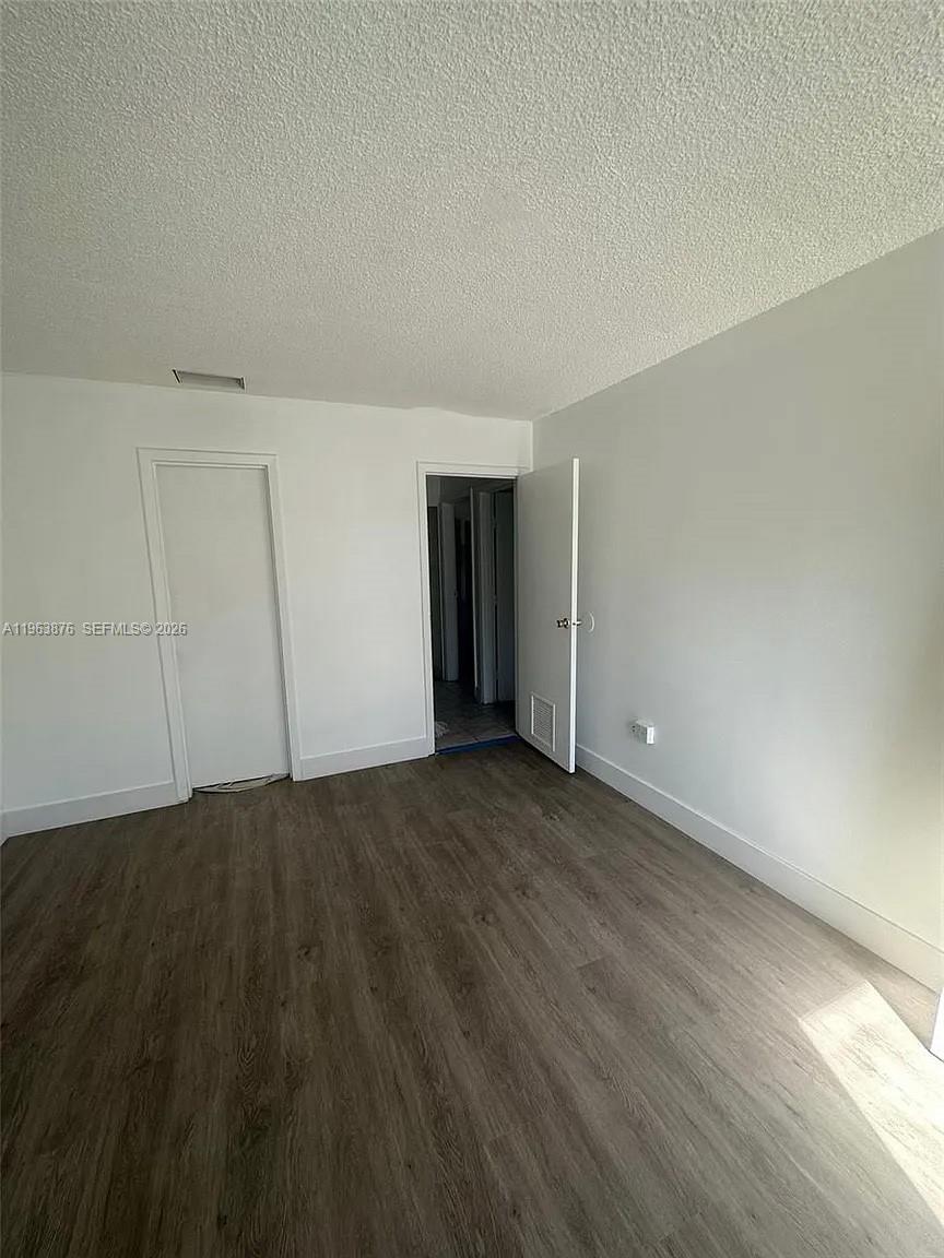 A room with white walls, a textured ceiling, and wood-look flooring features two doorways — 3020 E Missionwood Ln # 56, Miramar FL 33025, MIRAMAR, FL