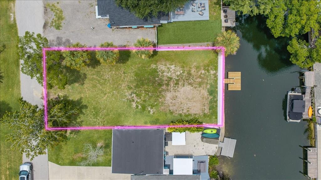 An aerial view shows a vacant rectangular waterfront lot outlined in pink with a dock — 7250 COVENTRY COURT, SPRING HILL, FL