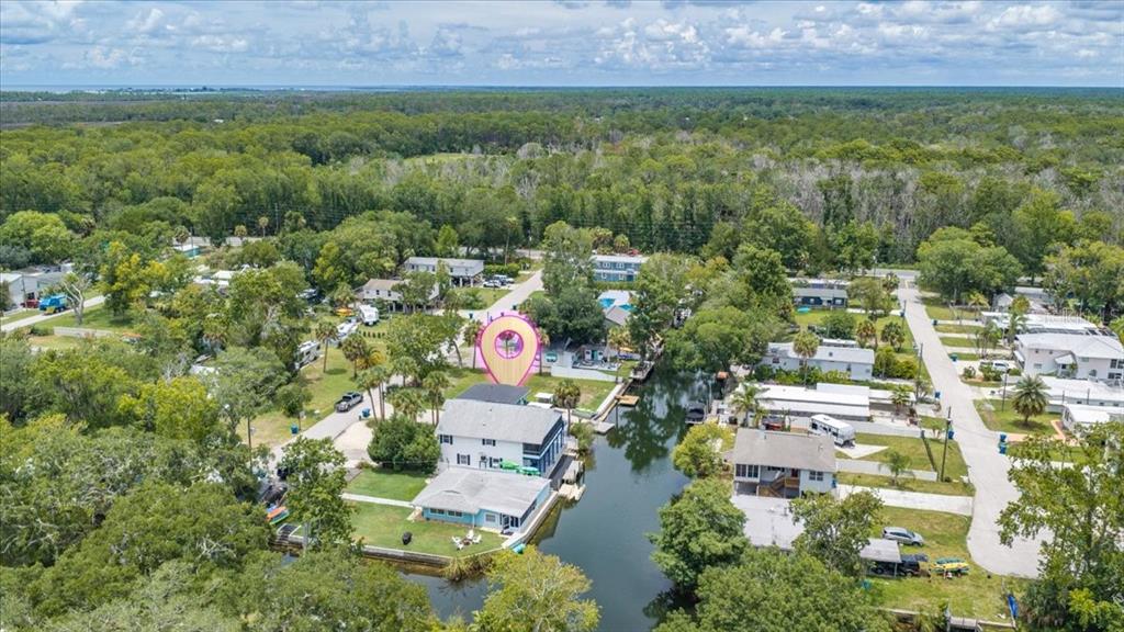 An aerial view shows a house with a canal, surrounding trees, and a location marker — 7250 COVENTRY COURT, SPRING HILL, FL