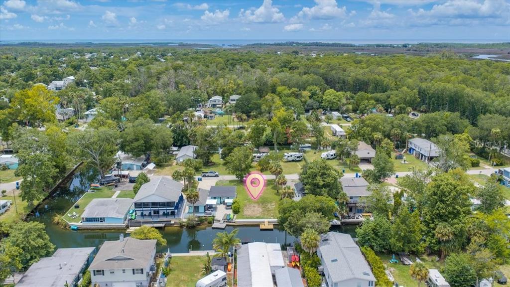 An aerial view shows a vacant waterfront lot marked with a pink pin — 7250 COVENTRY COURT, SPRING HILL, FL