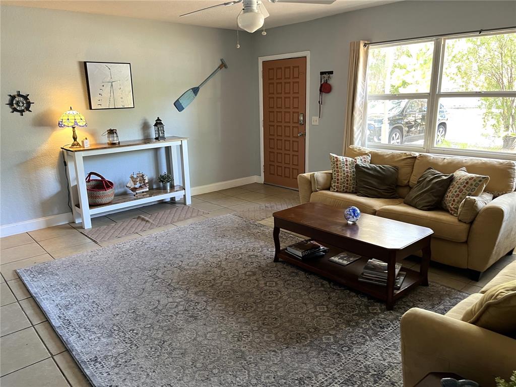 A living room features a tan sofa, a wooden coffee table, and a console table — 1358 N LOTUS DRIVE, DUNEDIN, FL